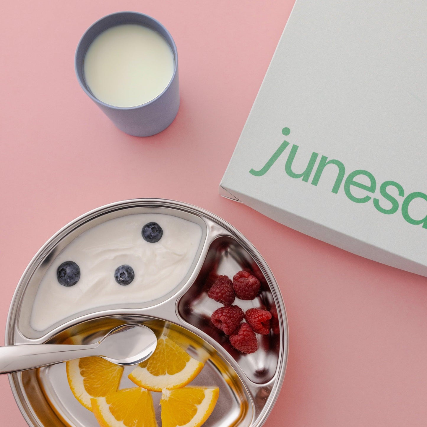 Healthy food placed inside the stainless steel plate complemented with a cup of milk and the product packaging.