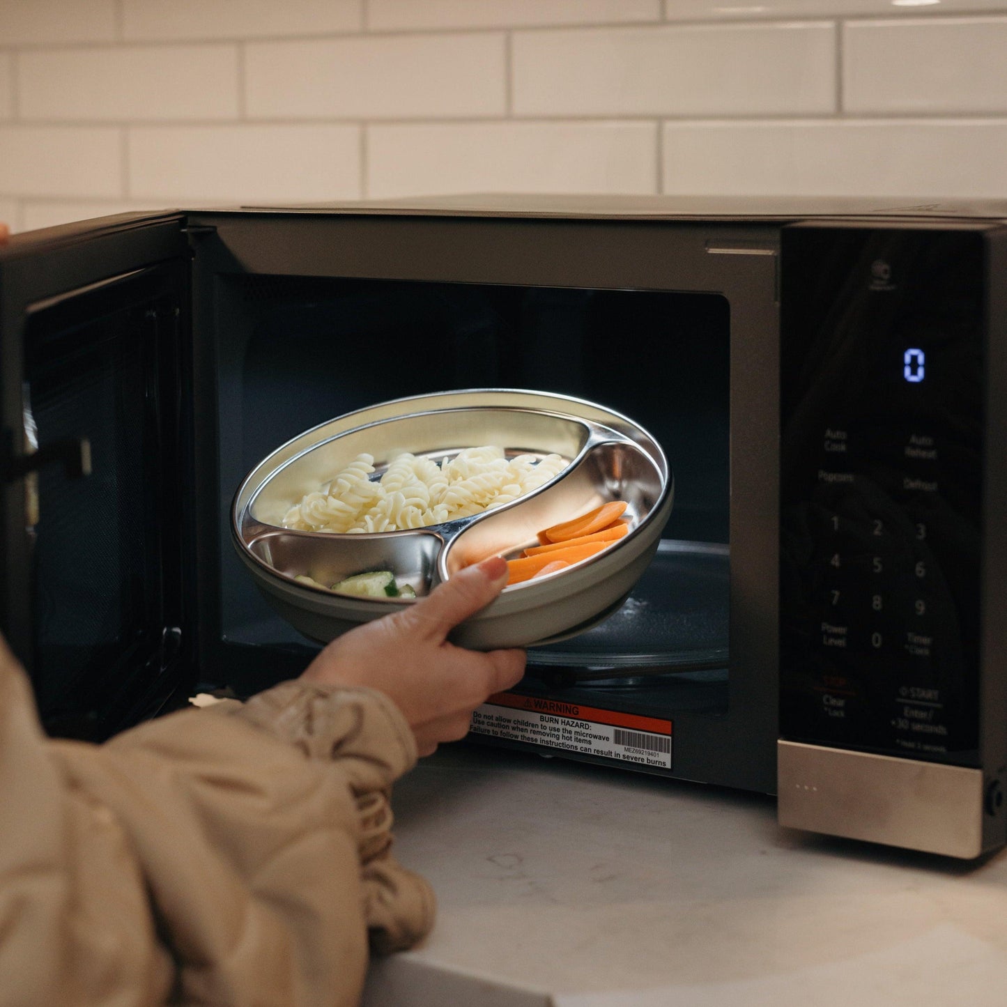 A model placing a stainless steel suction plate into the microwave.